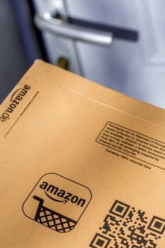 Paris, France - February 08, 2017: Delivery of a Amazon Prime Parcel Package in front the door of a house. Amazon, is an American electronic commerce and cloud computing company,based in Seattle, Started as an online bookstore, Amazon is become the most importrant retailer in the United States