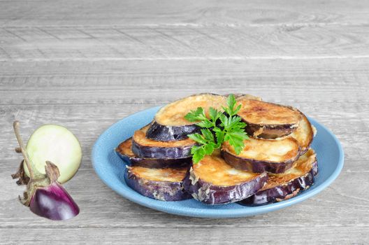 Fried eggplant on the blue plate, gray wood background.