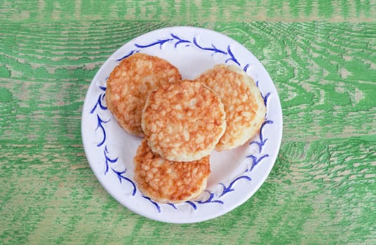 Rice patties in the plate on the old, green wooden background.