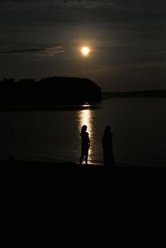 Peace tranquility - two female contour on a background of lake at sunset