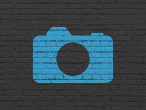 Tourism concept: Painted blue Photo Camera icon on Black Brick wall background