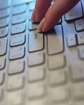 Woman fingers on the laptop keyboard in office
