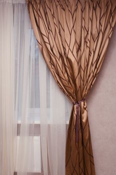 brown fabric curtain on the window in the bedroom.