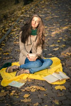 girl with a cup of coffee sitting in autumn Park