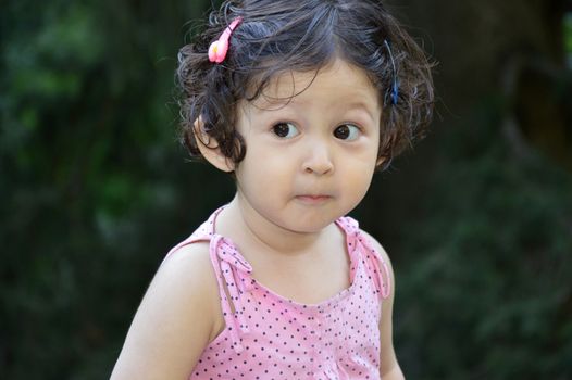 A three-year old little girl gives a look of surprise.