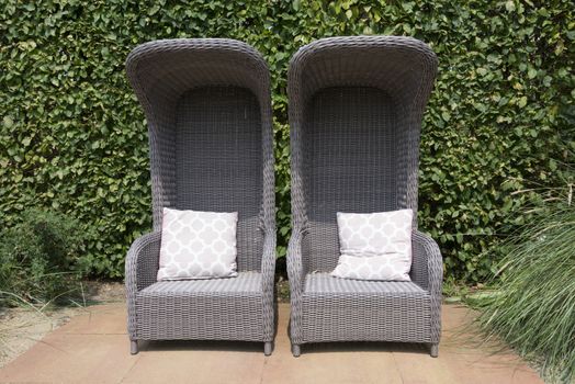 tow rattan armchairs in garden with ivy hedge as background