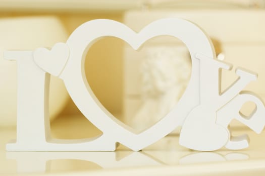 Wooden letters forming word LOVE written with angel on background
