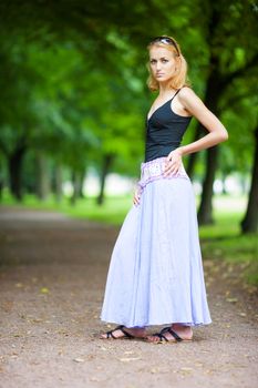 Sad woman standing in summer park waiting