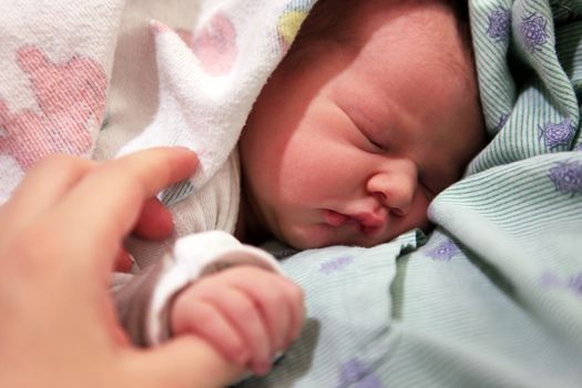 Sleeping newborn baby in the arms of my mother in hospital