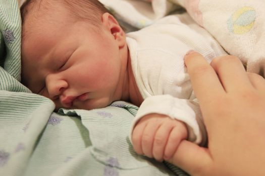 Sleeping newborn baby in the arms of my mother in hospital