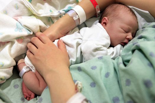 Sleeping newborn baby in the arms of my mother in hospital