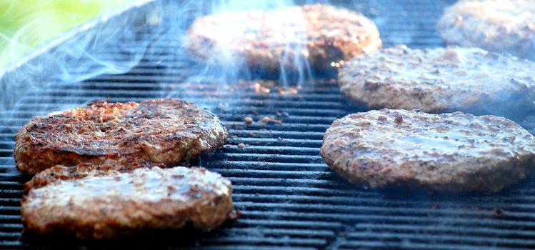 Hamburgers cooking on grill outdoors.