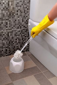 cleaning of white toilet bowl in yellow rubber gloves