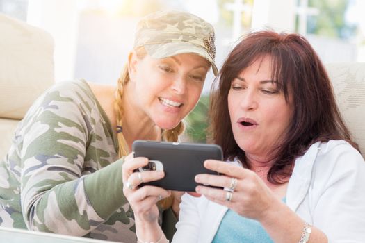 Two Female Friends Laugh While Using A Smart Phone on the Patio.
