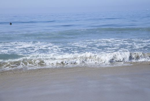 Heavy, foamy waves lapping at the ocean shore