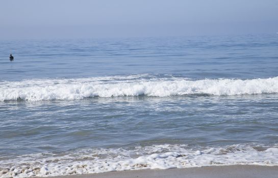 Heavy, foamy waves lapping at the ocean shore