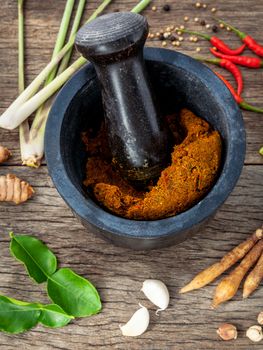 Assortment of Thai food Cooking ingredients and spice red curry paste ingredient of thai popular food on rustic wooden background. Spices ingredients chilli ,pepper, garlic and Kaffir lime leaves .