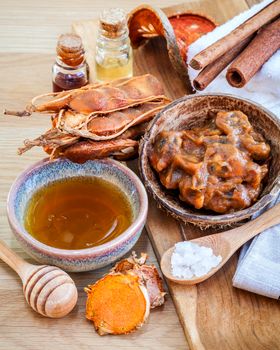 Homemade skin care and body scrub with natural ingredients tamarind, honey, himalayan salt ,turmeric and cinnamon set up on wooden background.