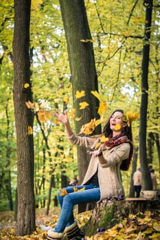 girl throws up leaves in autumn Park