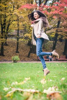 smiling, happy girl jumping on green grass in autumn park