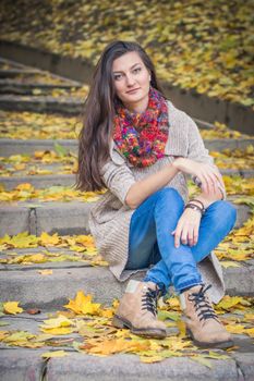 girl sitting on stone steps in autumn Park