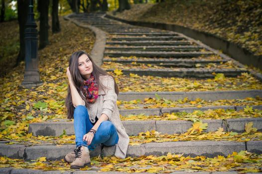 girl sitting on stone steps in autumn Park