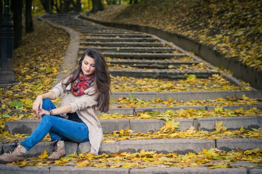 girl sitting on stone steps in autumn Park