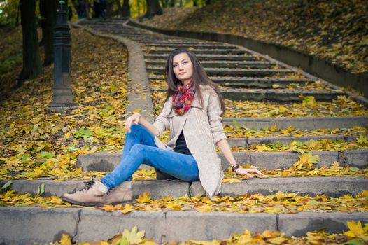 girl sitting on stone steps in autumn Park