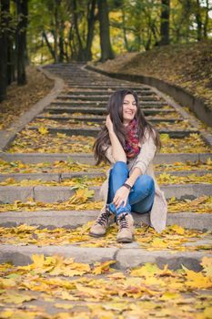 girl sitting on stone steps in autumn Park