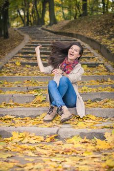 girl sitting on stone steps in autumn Park