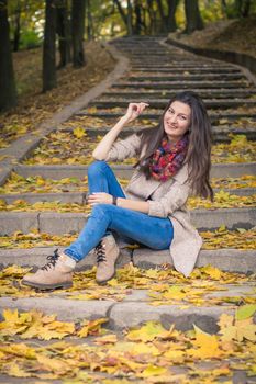 girl sitting on stone steps in autumn Park