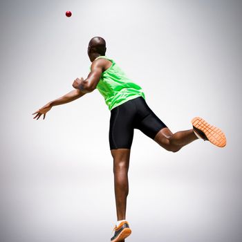Rear view of sportsman throwing a shot against grey background