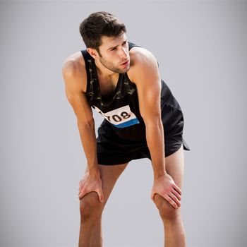 Athletic man resting with hands on knees against light grey