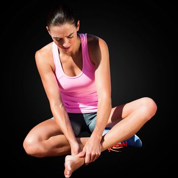 Sportswoman is hurting her foot in a black background