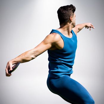 Side view of man throwing discus against grey background