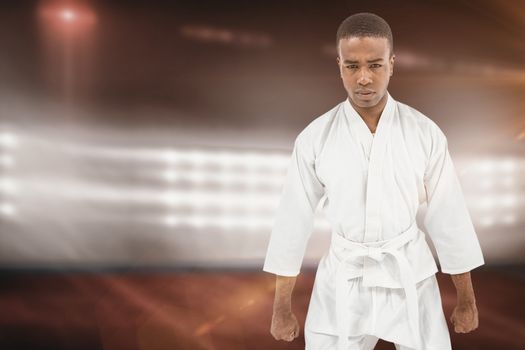 Front view of karate fighter meditating against composite image of playing field indoor