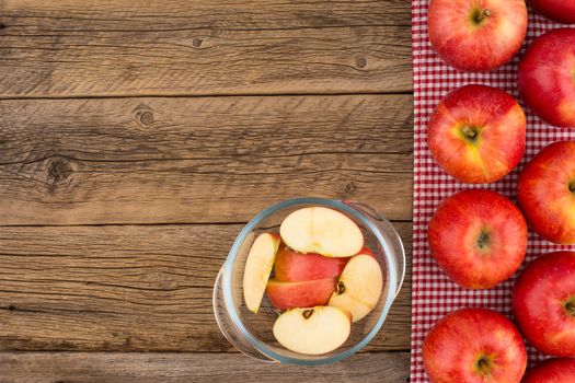 Sliced apples in a glass bowl on the old wooden table. Top view.