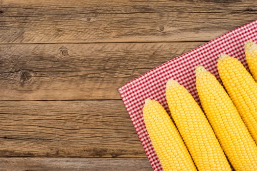 Fresh corn on cobs on rustic wooden table. Top view.