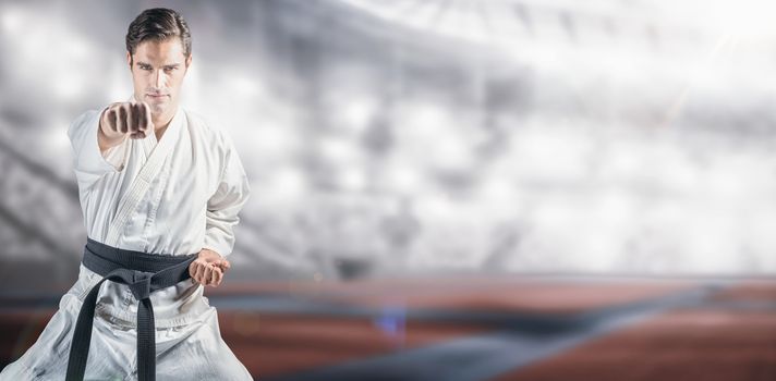 Portrait of fighter performing karate stance against composite image of american stadium