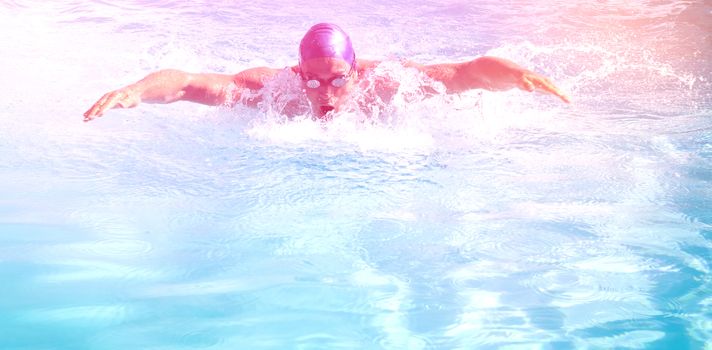 Fit swimmer doing the butterfly stroke in the swimming pool on a sunny day