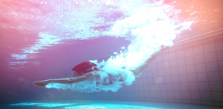 Athletic swimmer smiling at camera underwater in the swimming pool at the leisure centre