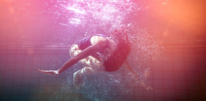 Athletic swimmer doing a somersault underwater in the swimming pool at the leisure centre