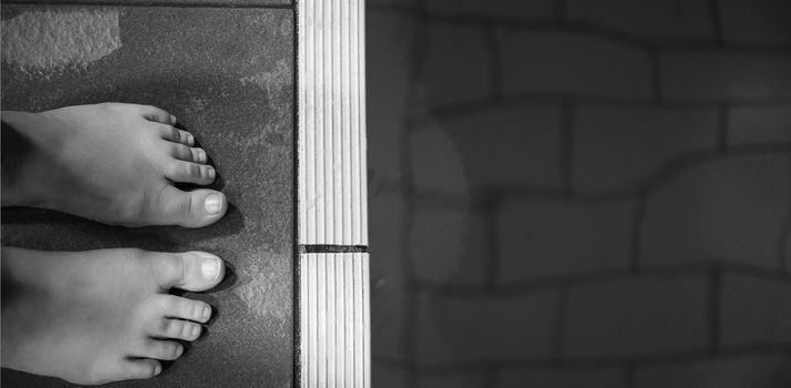 Feet of woman standing on the edge of the pool at the leisure center