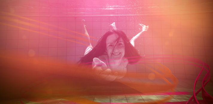 Pretty brunette smiling and offering her hand underwater in the swimming pool at the leisure centre