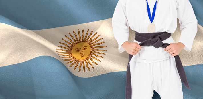 Fighter posing with medal around his neck against digitally generated argentina national flag