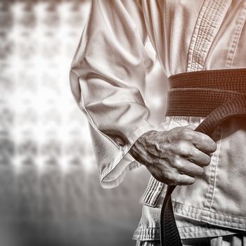 Fighter tightening karate belt against spotlights