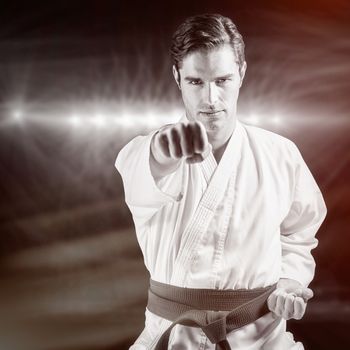Portrait of fighter performing karate stance against spotlights