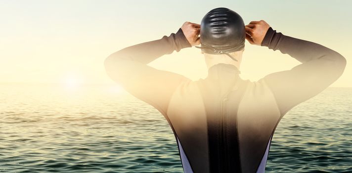 Rear view of swimmer in wetsuit wearing swimming goggles against beautiful day in the water