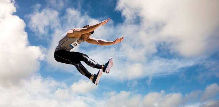 Portrait of sportsman jumping  against scenic view of blue sky