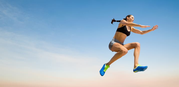 Sporty woman jumping against scenic view of blue sky